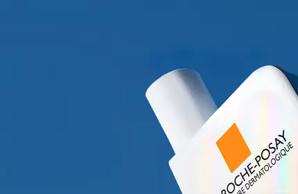 La Roche-Posay Sunscreen bottle peeking out from corner on a blue background